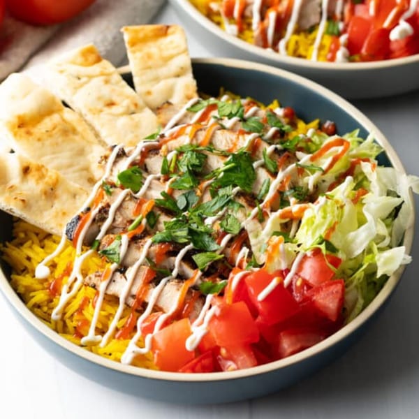 Gyro King Grill's chicken rice bowl with pita bread, lettuce, tomatoes, and sauces.